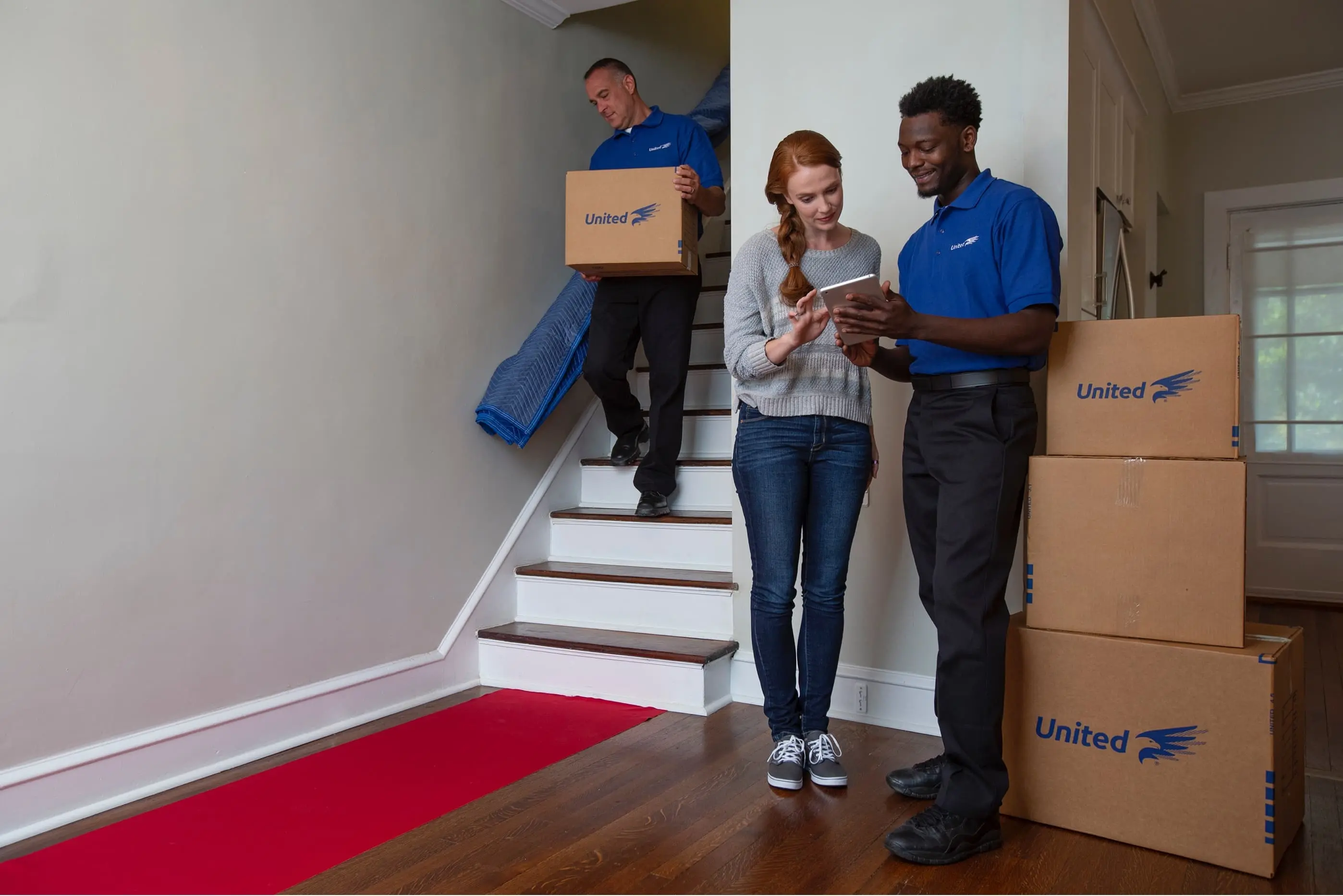 customer speaking with a United mover in her entry way with a second mover carrying a box downstairs